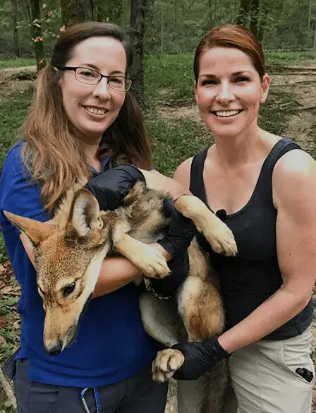 two women posing for a picture with a dog