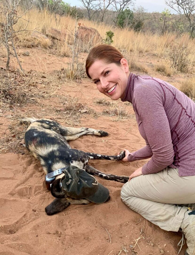 A woman kneeling down next to an animal.