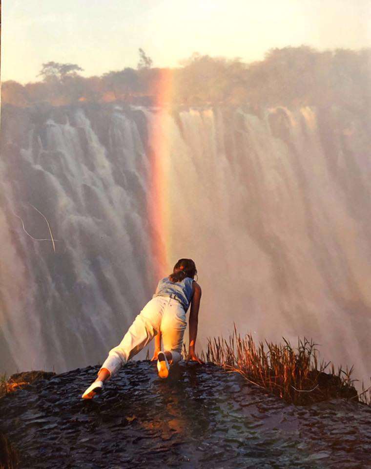 A person standing on top of a mountain near a waterfall.