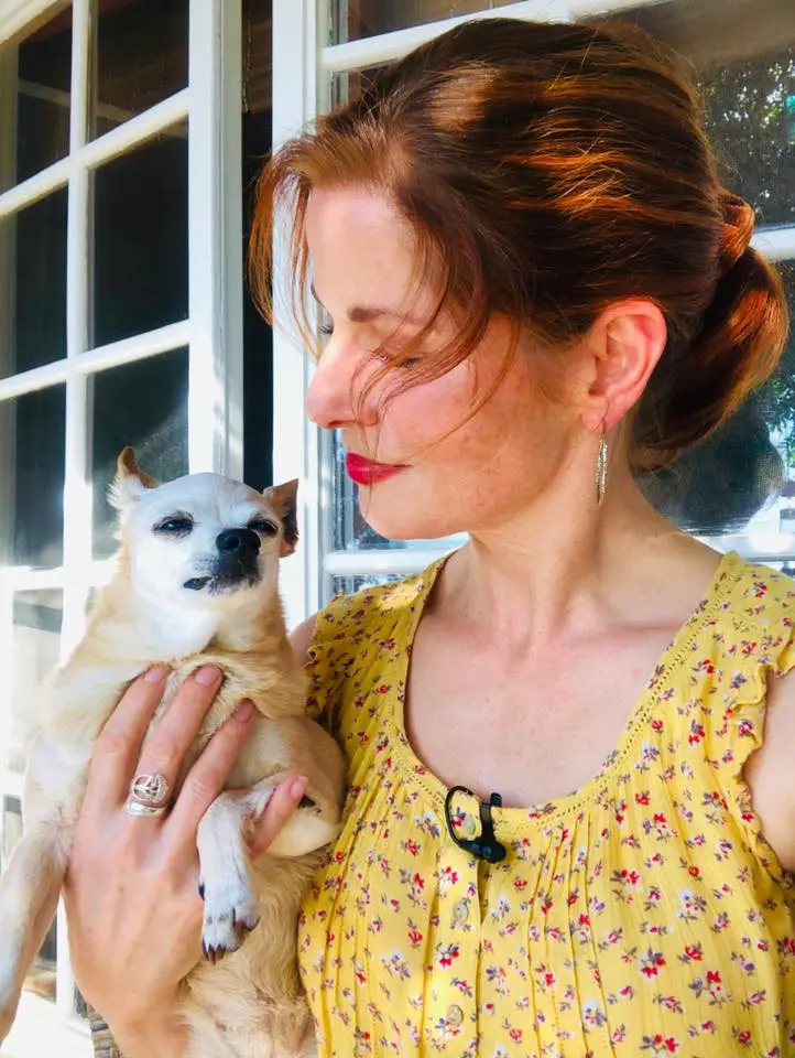 A woman holding a small dog in her arms.