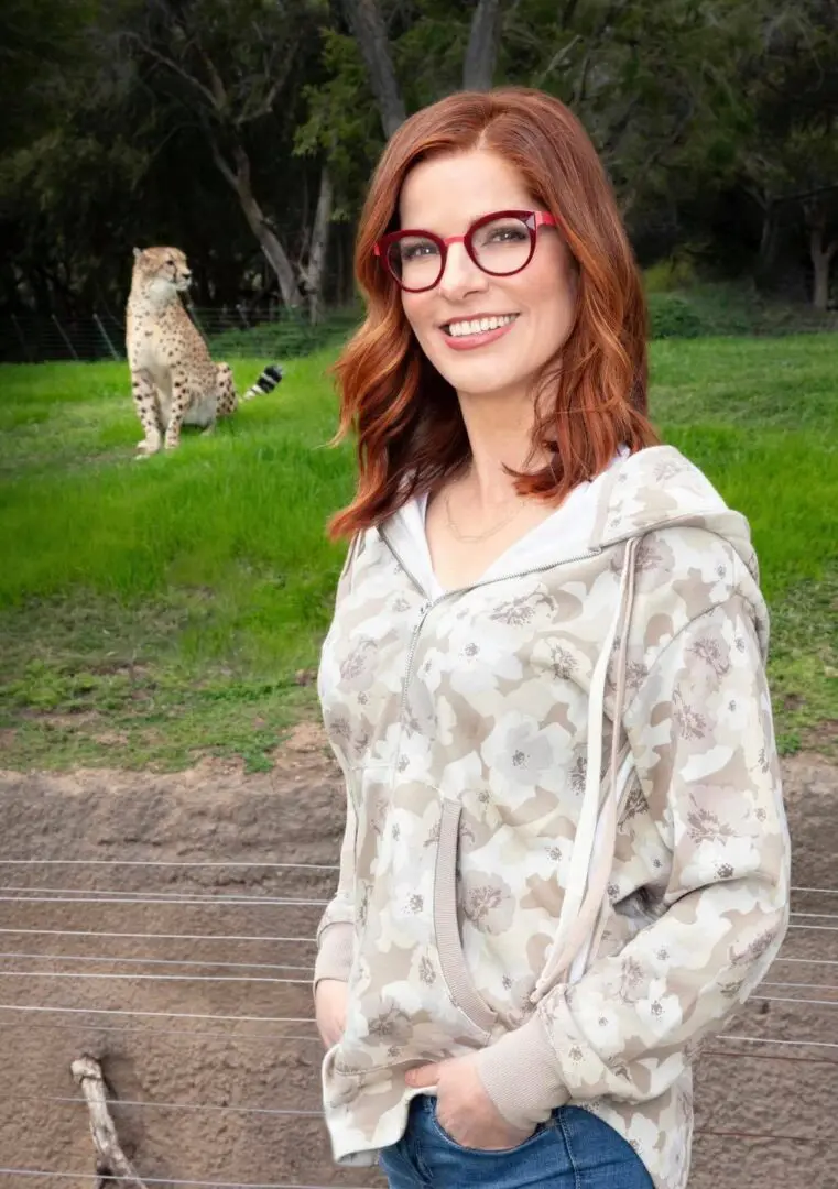 A woman standing in front of a tiger.