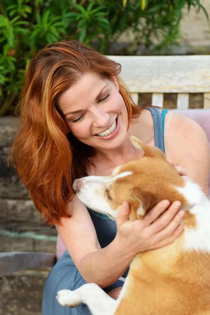 A woman holding onto a cat while smiling.