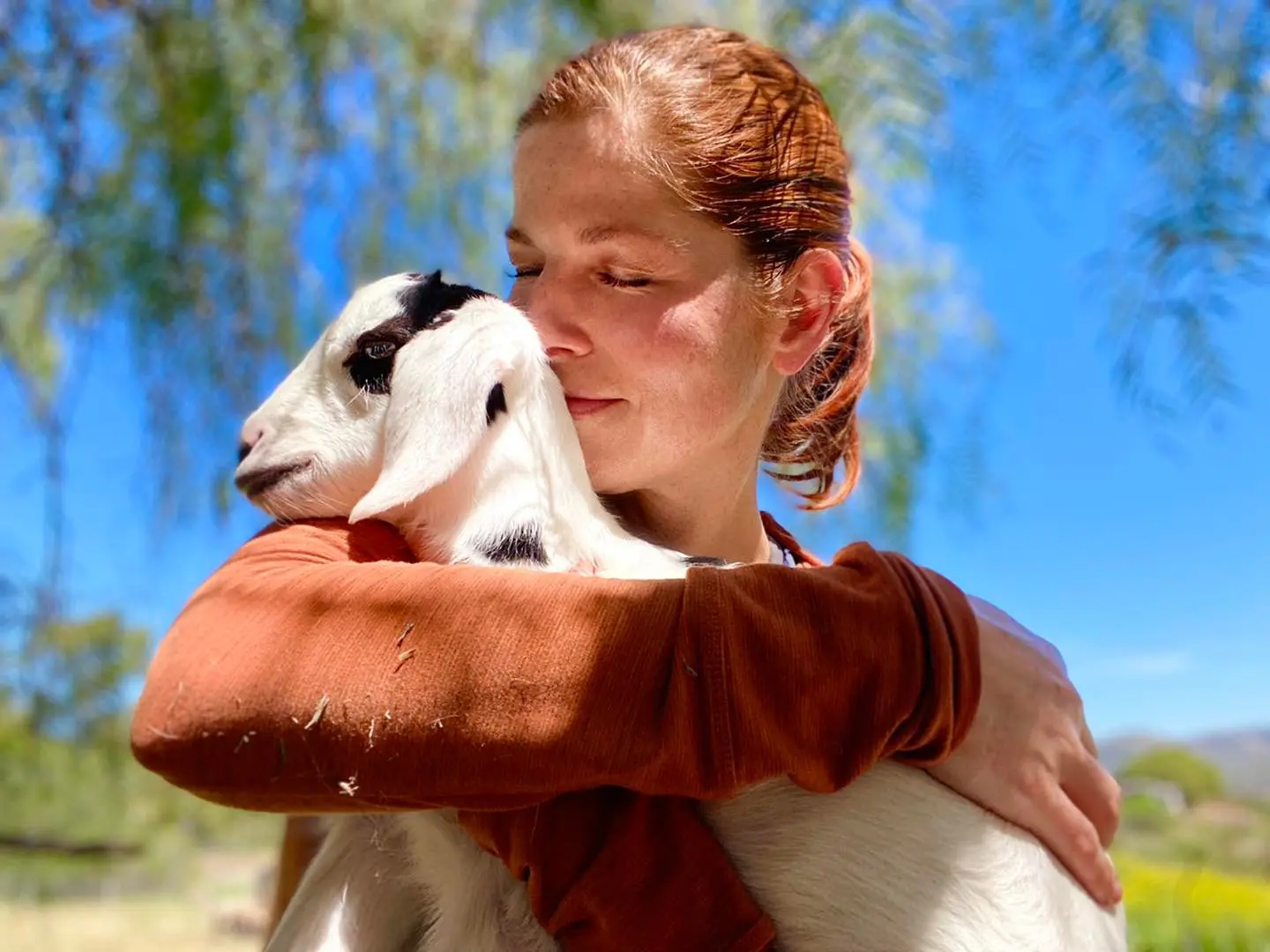 A woman holding a goat in her arms.