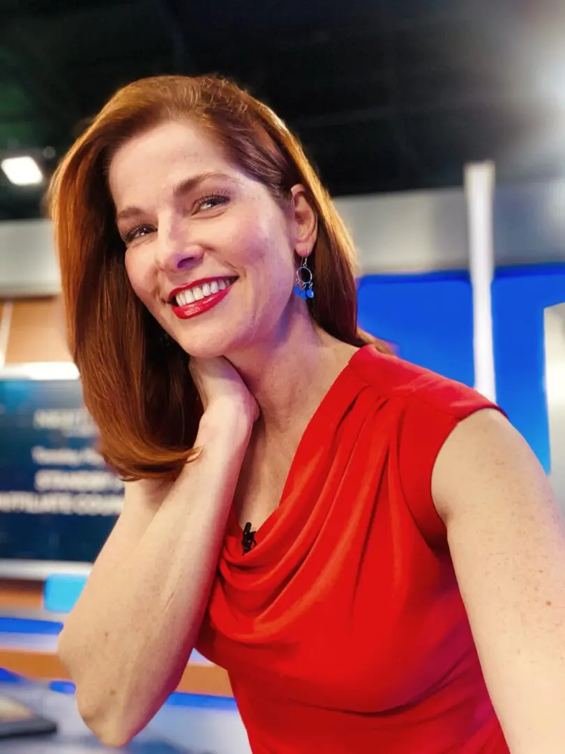 A woman in red is smiling for the camera.
